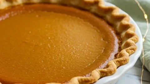 Delicious classic pumpkin pie topped with whipped cream on a rustic table.