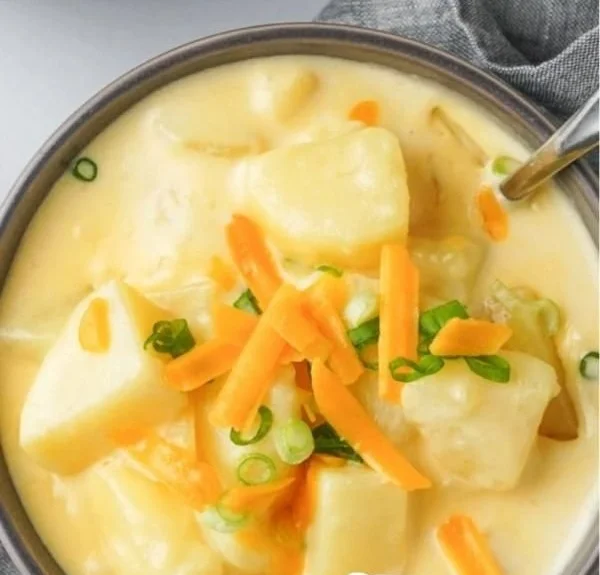 Bowl of creamy cheesy potato soup garnished with herbs