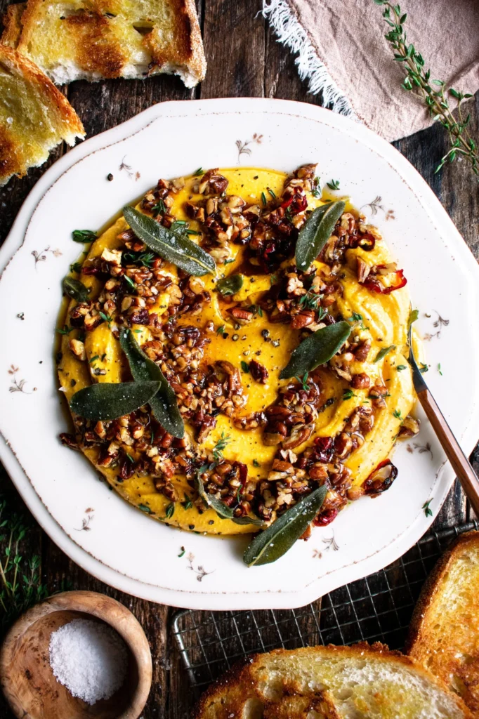 Creamy roasted honeynut squash feta dip served in a bowl with herbs