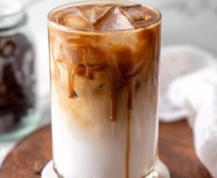 Iced Caramel Macchiato topped with creamy foam and drizzled caramel sauce