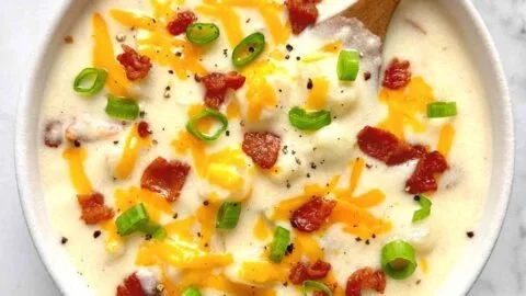 A hearty bowl of loaded potato soup topped with cheese and green onions.