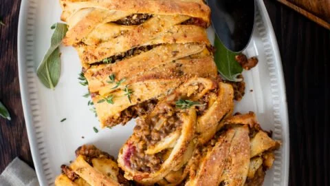 Vegan Lentil Stromboli with fresh vegetables and herbs on a wooden table.